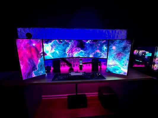 Triple gaming monitor setup with RGB lighting and desktop PC on a modern desk
