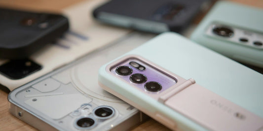 Close-up of several smartphones arranged on a wooden surface, with a mint green foldable phone and its triple-camera system in focus.