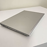 Closed silver HP laptop with ports on side, on white desk, refurbished electronics